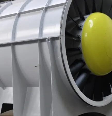 Industrial tube-axial ventilation fan with aerofoil blades and yellow nose cone in a factory