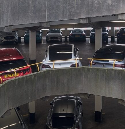 Interior of an enclosed multi-storey car park with parked cars, concrete decks and a spiral ramp