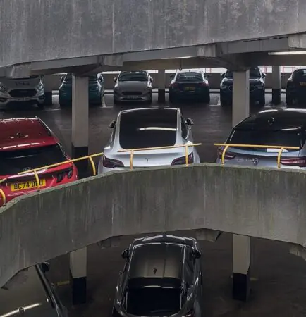 Interior of an enclosed multi-storey car park with parked cars, concrete decks and a spiral ramp
